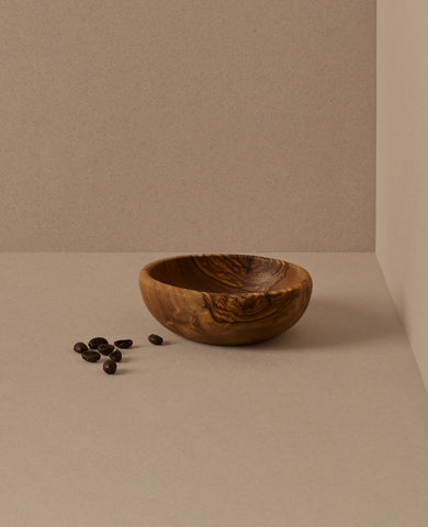 A set of natural olive wood bowls in various sizes, with the smallest bowls containing lemons. The bowls display a beautiful wood grain pattern.