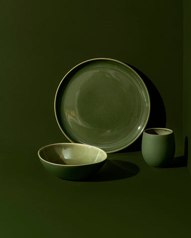 A set of white stoneware dinnerware including a flat salad plate, a dinner bowl, and a mug.