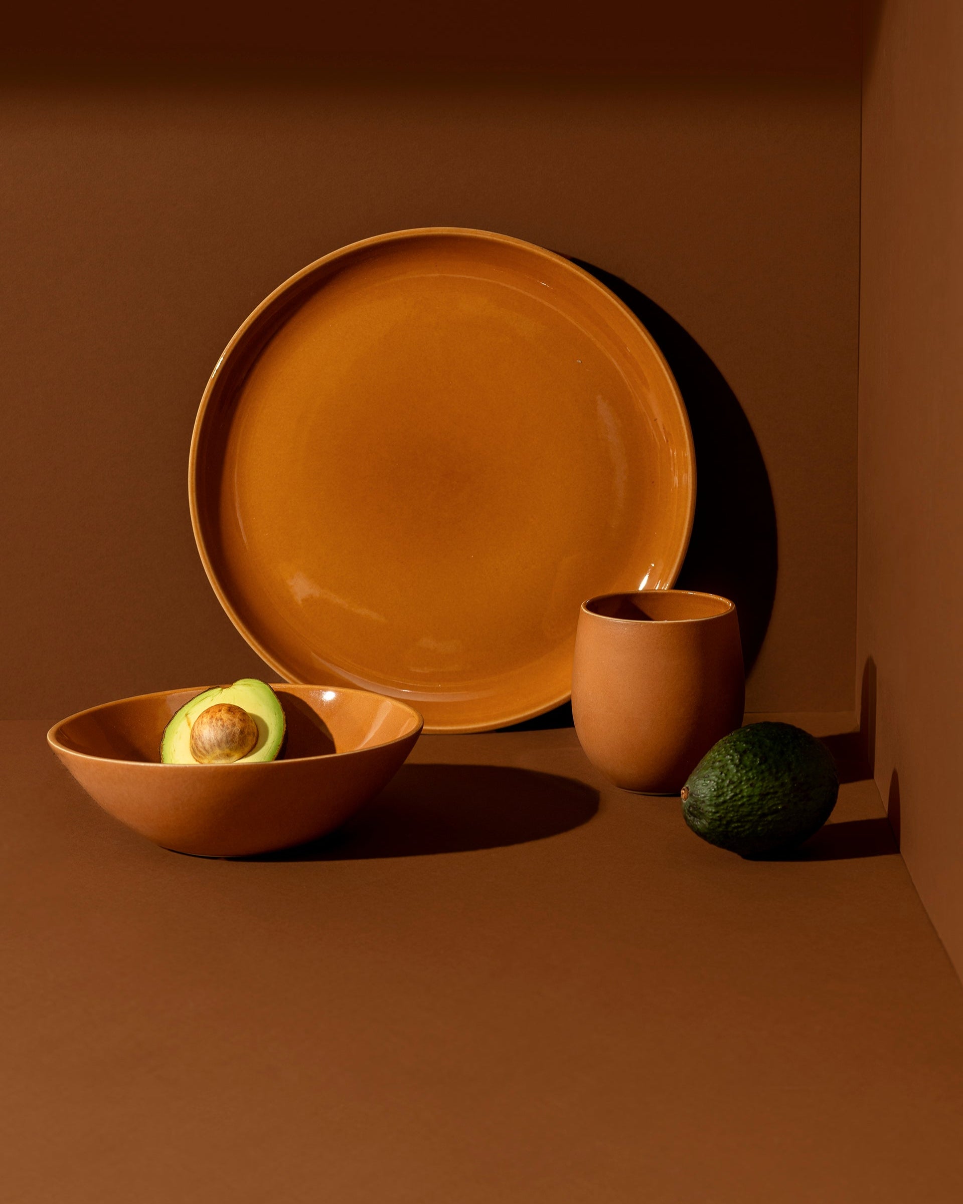 A set of white stoneware dinnerware including a flat salad plate, a dinner bowl, and a mug.