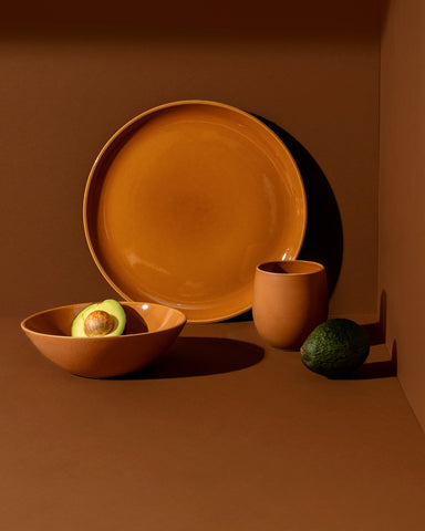A set of white stoneware dinnerware including a flat salad plate, a dinner bowl, and a mug.